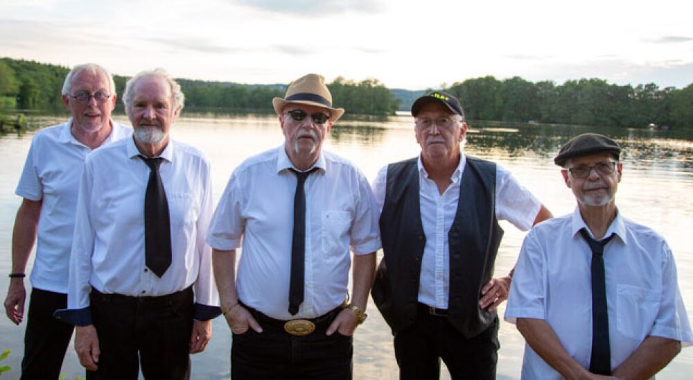 De fem medlemmer af The Old Hounddogs fotograferet ved en sø i aftenlys